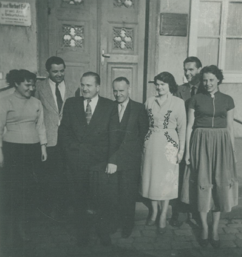 Historisches Schwarz-Weiß-Foto aus dem Jahr 1945: Eine Gruppe von sechs Personen, darunter Dr. Adolf Annecke, steht vor dem Gebäude der neu gegründeten Treuhand- und Buchstelle.